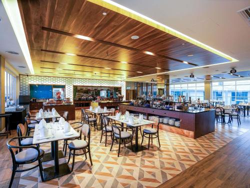 a restaurant with tables and chairs and a bar at Mercure Langkawi Pantai Cenang in Pantai Cenang