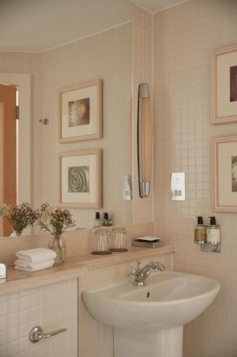 a white bathroom with a sink and a mirror at Braye Beach Hotel, Alderney in Alderney