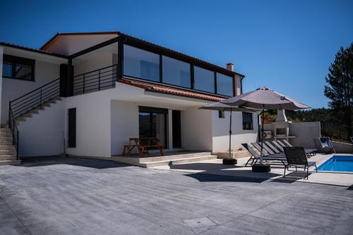 a house with a swimming pool and an umbrella at Recanto da Boucinha - T2 in Veade