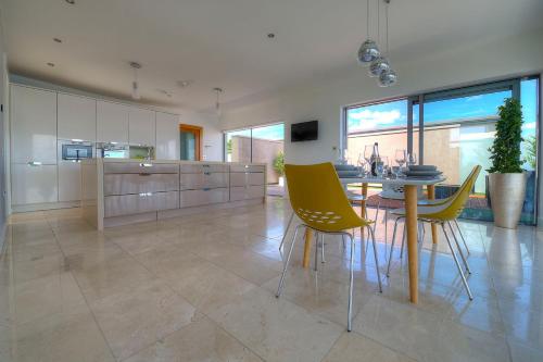 a kitchen with a dining table and yellow chairs at Tur an Tsaile - Galway Lakeside Apartments in Galway