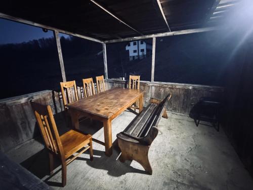 une table et des chaises en bois et un banc dans une pièce dans l'établissement Cabana Valea Lungă, à Telcişor