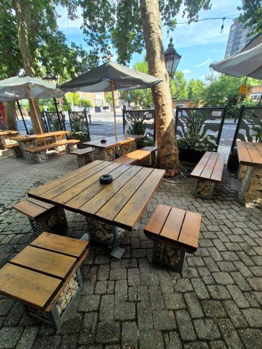 a wooden picnic table with benches and umbrellas at The Warrington in London