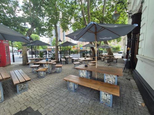a group of tables and benches with umbrellas at The Warrington in London