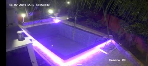 ein Schwimmbad bei Nacht mit roten und violetten Lichtern in der Unterkunft Om sai villa in Neral