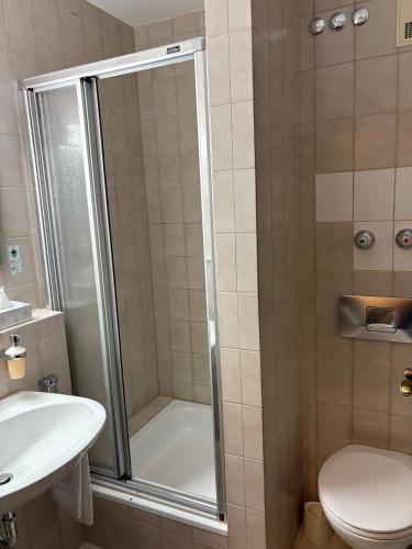 a bathroom with a shower with a toilet and a sink at Hotel Gumberger GmbH Garni in Neufahrn bei Freising