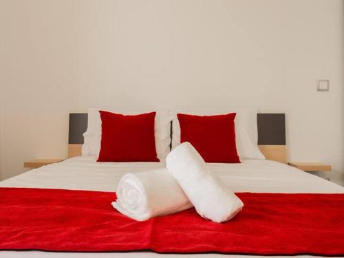 a white bed with red pillows and a red blanket at Skyline Villas Room in Calheta