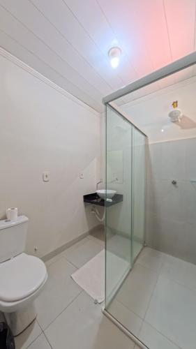 a bathroom with a toilet and a glass shower stall at Hotel Hawaii in Colíder