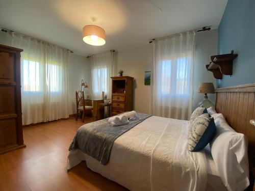 ein Schlafzimmer mit Bett, Tisch und Fenstern in der Unterkunft Casa Rosiña in Campo Lameiro
