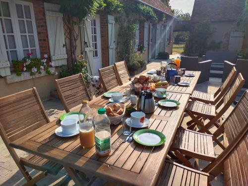 ein Holztisch mit Tellern voller Essen darauf in der Unterkunft Par les Prés et les Bois de Sologne in Bauzy
