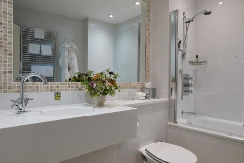 a white bathroom with a toilet and a sink at Fermain Valley Hotel in St. Peter Port