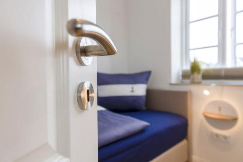 a door with a blue bed in a room with a window at Haus Dünenperle, Ferienwohnung Dünengras in Wittdün