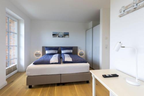 a bedroom with a bed and a desk in it at Haus Dünenperle, Ferienwohnung Dünengras in Wittdün