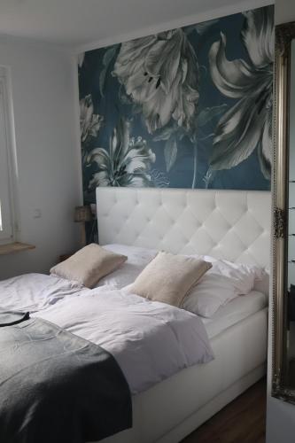 ein Schlafzimmer mit einem weißen Bett mit Blumentapete in der Unterkunft Ferienhaus Kleiner Muck in Glückstadt