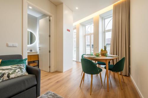 a living room with a table and green chairs at Casa da Cónega by Sé Apartamentos in Braga