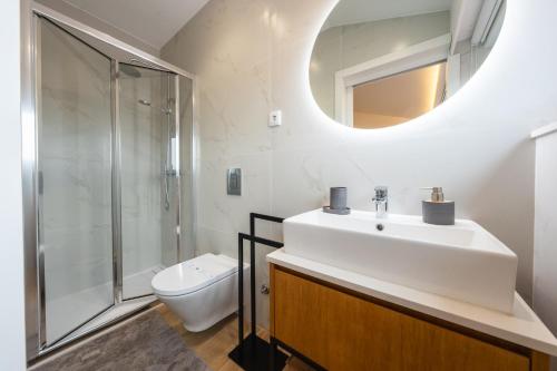 a bathroom with a sink and a toilet and a mirror at Casa da Cónega by Sé Apartamentos in Braga