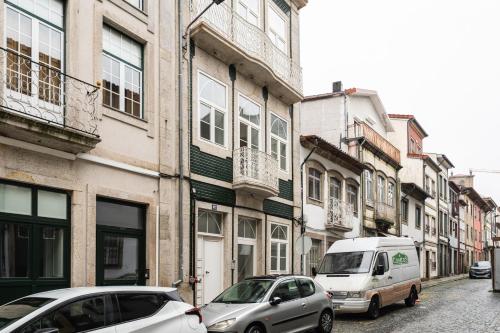 two cars parked on a street next to buildings at Casa da Cónega by Sé Apartamentos in Braga