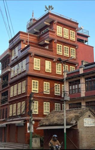 un alto edificio di mattoni con finestre e un uomo su una motocicletta di DND House a Patan