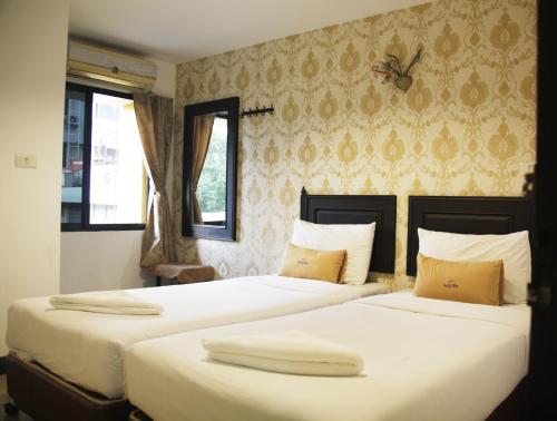 two beds in a bedroom with a butterfly on the wall at Erawan House in Bangkok