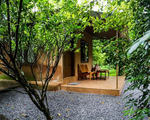 eine Person, die auf einer Bank auf einem Holzdeck sitzt in der Unterkunft DJ River Meadows By Let's Inn in Panamaram