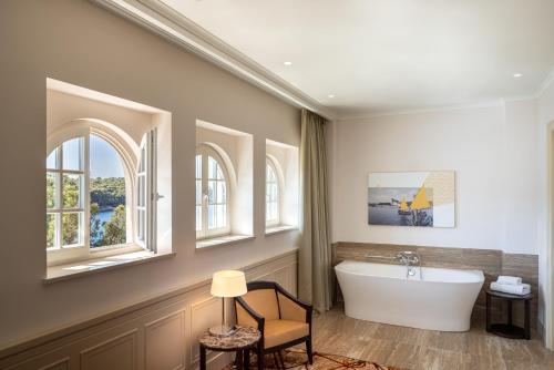 ein Badezimmer mit einer Badewanne und zwei Fenstern in der Unterkunft Boutique Hotel Alhambra in Mali Lošinj