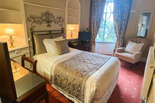 a bedroom with a large bed and a chair at Stow Lodge Hotel in Stow on the Wold
