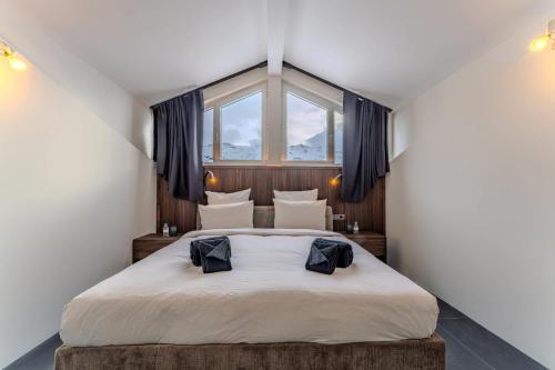 een slaapkamer met een groot bed en een raam bij Luxurious Penthouse Lumina - Fire place, Pool and Spa in Val Thorens