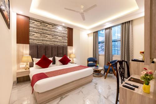 a bedroom with a bed with red pillows and a desk at Hotel East End Delhi Airport in New Delhi
