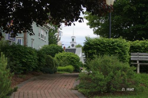 a brick walk way with a clock tower in the background at Bucksport Inn in Bucksport