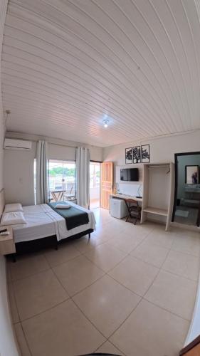 a large room with a bed and a television at Hotel Hawaii in Colíder