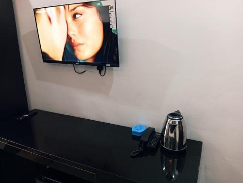 een flatscreen-tv hangend aan een muur boven een tafel bij Heirloom Luxury Hotel and Apartments in Maiyegun