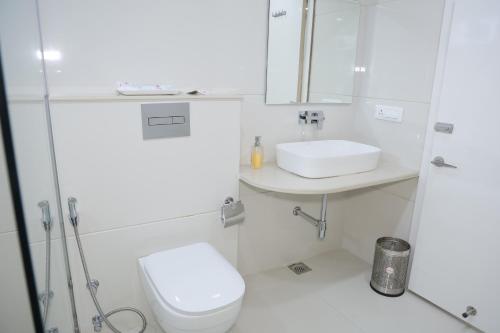 a white bathroom with a toilet and a sink at Avadh Hotel & Banquets in Bareilly