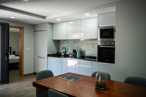 a kitchen with white cabinets and a wooden table at Recanto da Boucinha - T3 in Veade