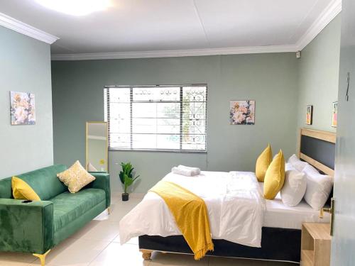 a bedroom with a bed and a green couch at Stay Arcadia Guest House in Pretoria