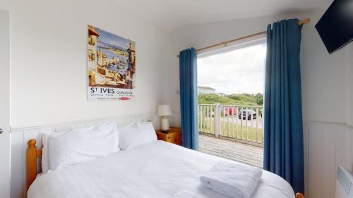 a bedroom with a bed and a large window at C25 Weir View, Riviere Towans in Hayle
