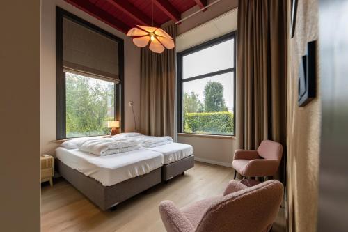 ein Schlafzimmer mit einem Bett und zwei Stühlen und einem Fenster in der Unterkunft Groepsaccommodatie De Landerij in Scherpenzeel
