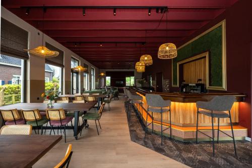 ein Restaurant mit Tischen und Stühlen und eine Bar in der Unterkunft Groepsaccommodatie De Landerij in Scherpenzeel