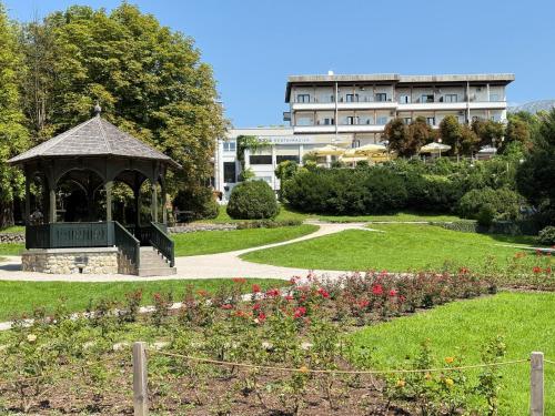 a gazebo in a garden with a building in the background at Lakefront Bled - Rooms & Apartments in Bled