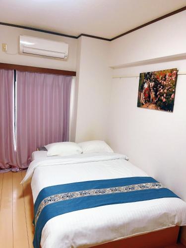 a bedroom with a large bed with a painting on the wall at Sea Bloom Hotel in Nagasaki