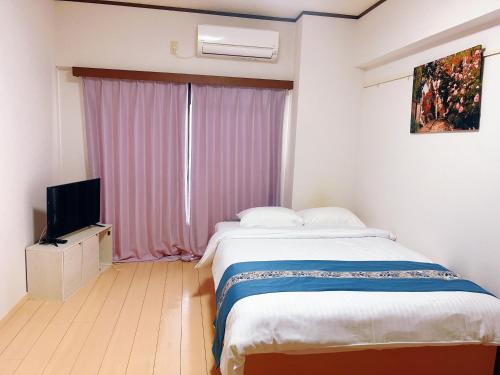 ein Schlafzimmer mit einem großen Bett und einem Fernseher in der Unterkunft Sea Bloom Hotel in Dejimamachi