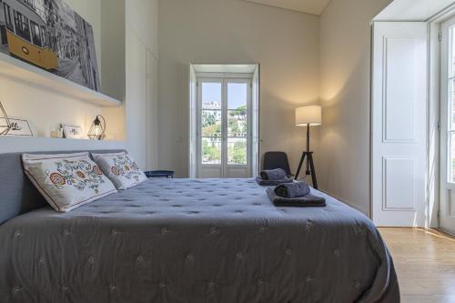 a bedroom with a bed with blue sheets and a window at Lagares 74 in Lisbon