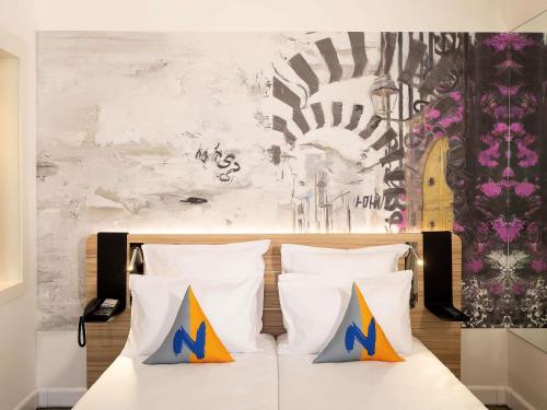Schlafzimmer mit einem Bett mit weißer Bettwäsche und bunten Kissen in der Unterkunft Novotel Tunis Lac in Tunis