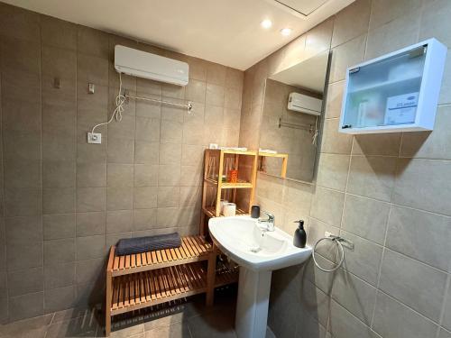 een badkamer met een wastafel en een tv aan de muur bij El Loft de Salàs - L'Amfitriona in Salás de Pallás