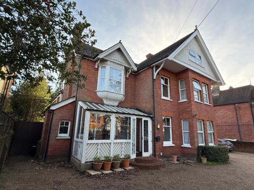 a red brick house with white windows and potted plants at Wimblehurst Hotel in Horsham