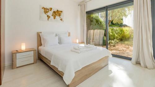 a bedroom with a bed and a large window at Cavalo Preto Ocean Breeze Apartment in Forte Novo Quarteira in Quarteira