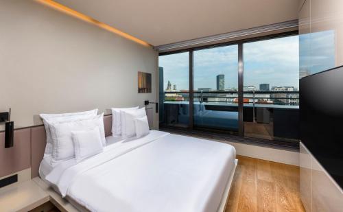 un letto bianco in una stanza con una grande finestra di SANA Berlin Hotel a Berlino