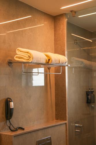 a bathroom with a shower with towels on a shelf at RATHNA RESIDENCY in Coimbatore