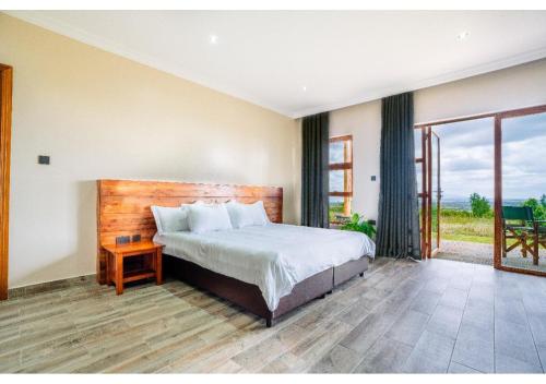 a bedroom with a bed and a large window at Inchorroi Cottages - champagne ridge in Oloyaingalani