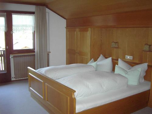 ein Schlafzimmer mit einem großen weißen Bett mit einem hölzernen Kopfteil in der Unterkunft Appartements am Stein in Bezau