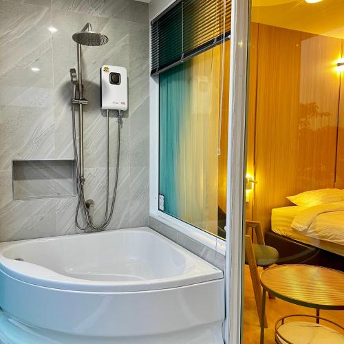 a bath tub in a bathroom with a bedroom at โรงแรมดีวิว โกลเด้นไทรแองเกิ้ล เชียงแสน - Dview Golden Triangle Hotel Chiangsaen in Golden Triangle