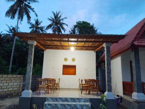 eine Terrasse mit Tischen und Stühlen vor einem Haus in der Unterkunft Santhi Laba Bungalow in Nusa Penida